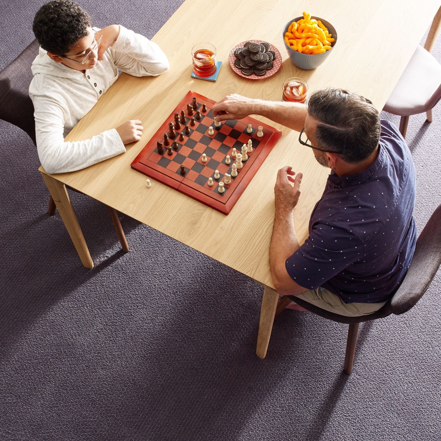 Here are some tips and tricks for preparing before your new floor arrives! | Family sitting across a table playing chess